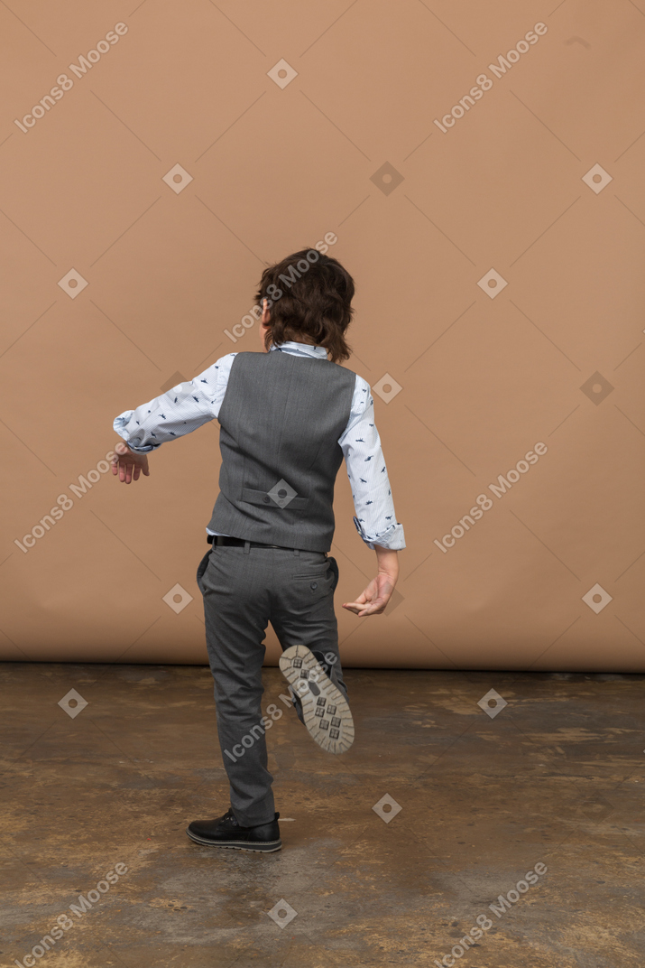 Rear view of a boy in grey suit walking