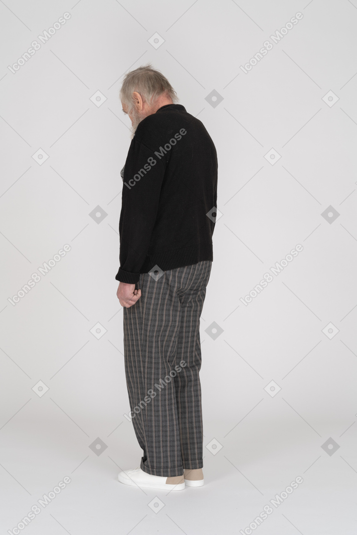 Three quarter back view of an old man standing with head down
