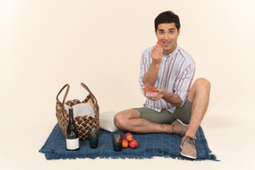 Junger kaukasischer kerl, der picknick hat und früchte isst