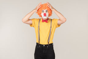 Troubled looking male clown touching wig he's wearing