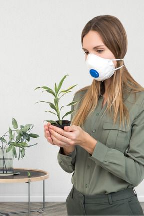 A woman wearing a face mask and holding a plant