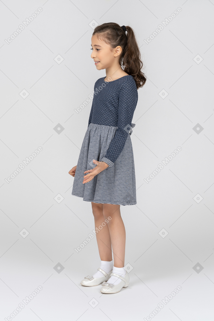 Three-quarter view of a girl smiling and gesturing awkwardly