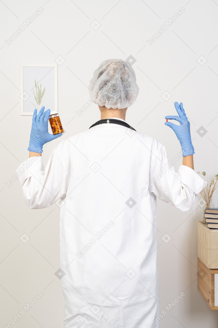 Back view of a young female doctor choosing between pills