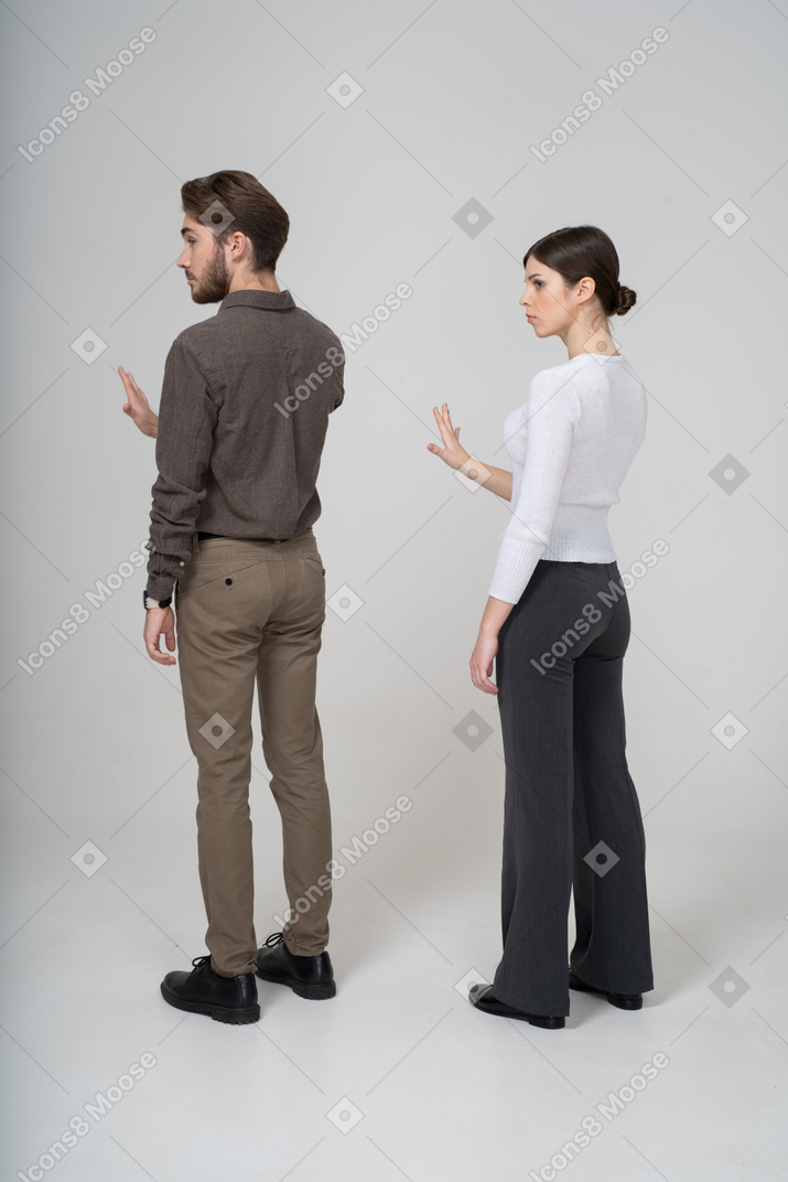 一对年轻夫妇在办公室服装伸出手中的四分之三视图
