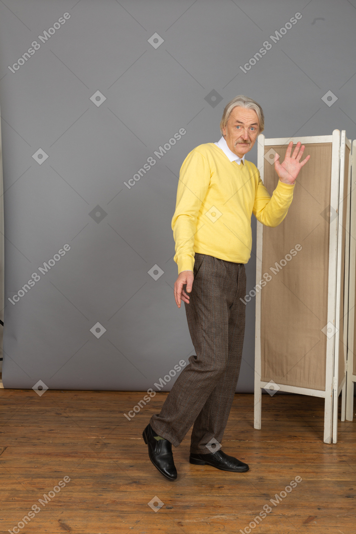 Full-length of a funny old man raising his hand for greeting