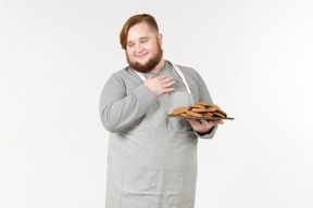 Un hombre gordo contento sosteniendo un plato de galletas