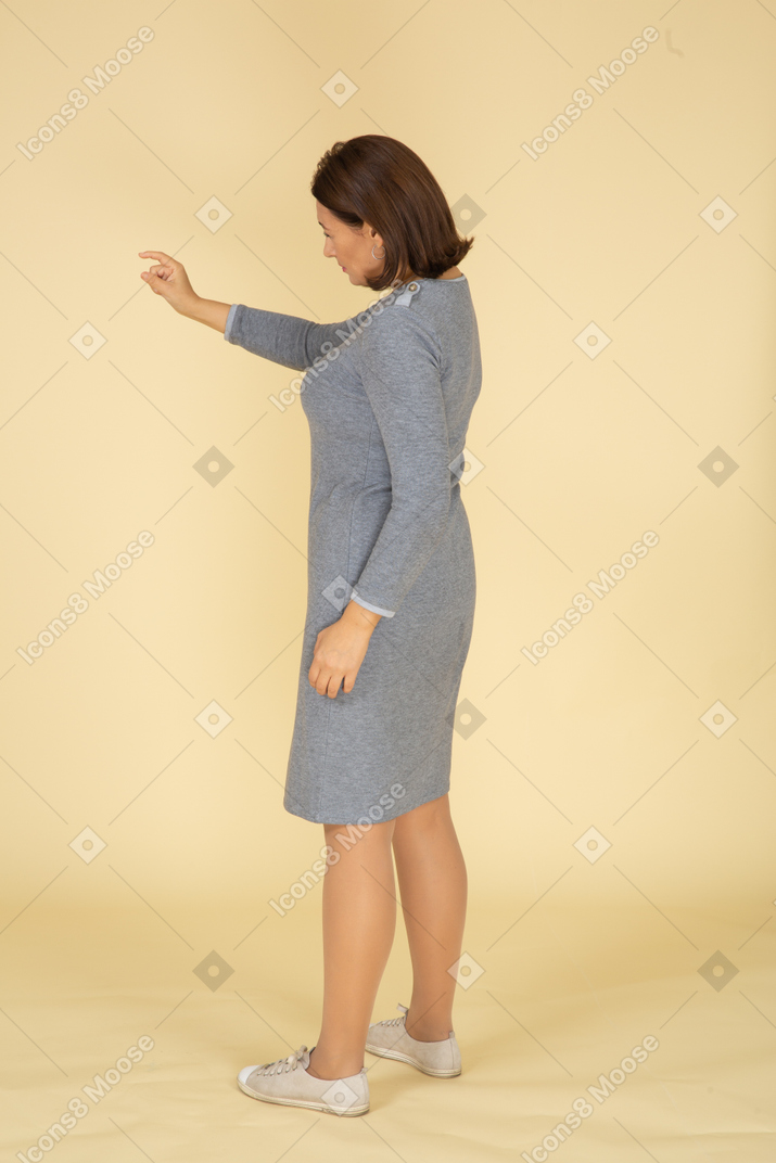 Vue latérale d'une femme en robe grise montrant une petite taille de quelque chose