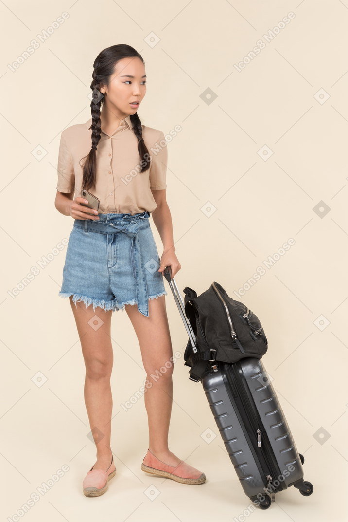 Viaggiatore femminile con bagagli distogliendo lo sguardo