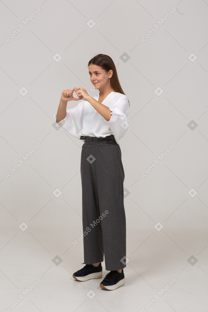 Three-quarter view of a young lady in office clothing showing heart gesture