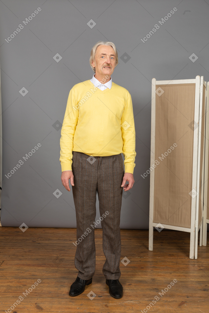 Vista frontal de um homem idoso com um pulôver amarelo olhando para o lado