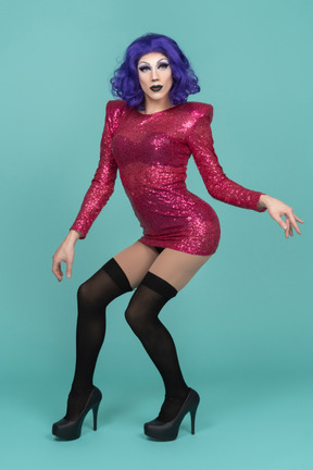 Front view of a drag queen in pink dress arching their back while posing