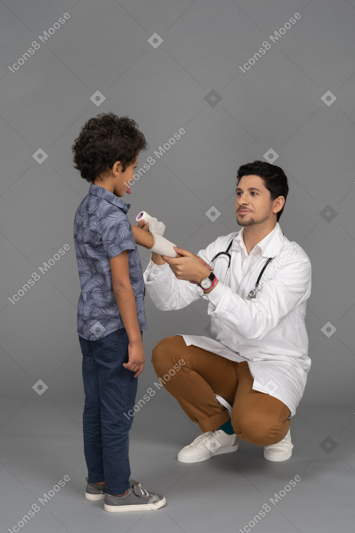 소년에게 붕대를 보여주는 의사