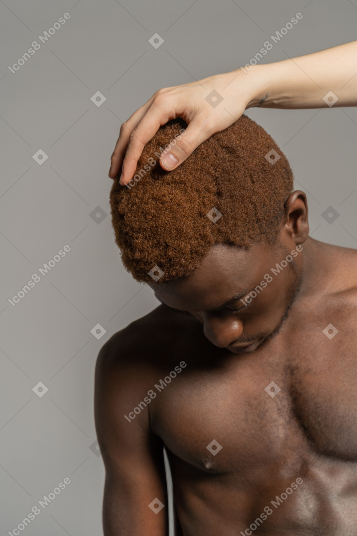 Mão branca tocando o cabelo de um jovem negro