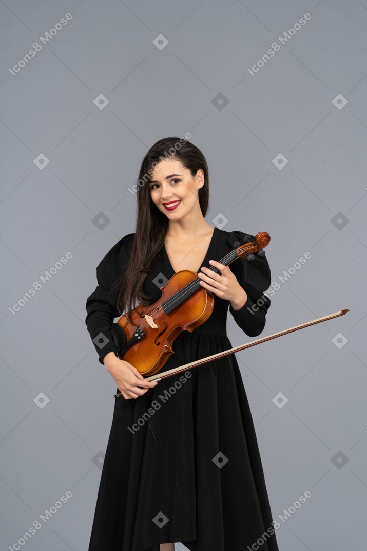 Close-up de uma jovem alegre de vestido preto segurando o violino