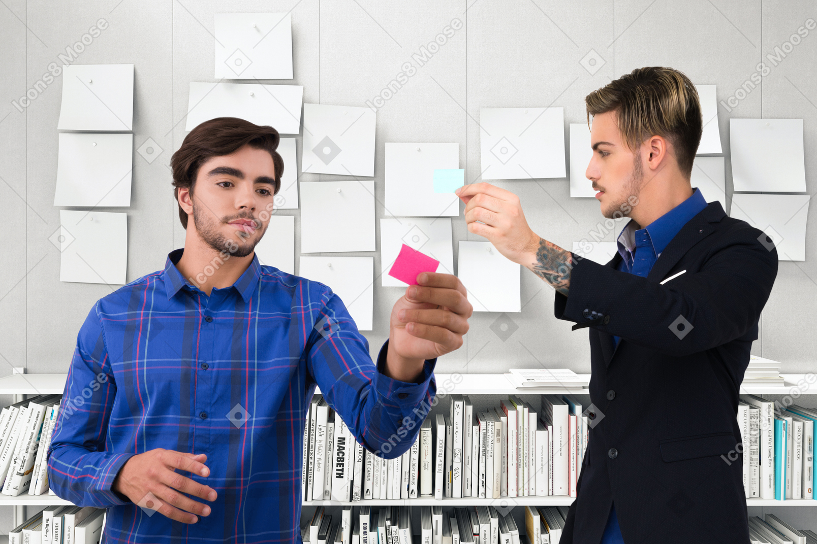 Two male office workers looking at notes and discussing something