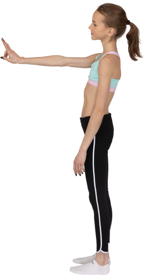 Side view of a cool teen girl in sportswear showing peace gesture