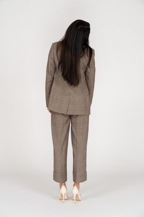 頭を回す茶色のビジネススーツの若い女性の背面図