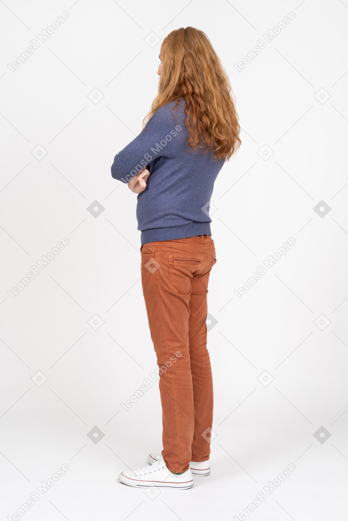 Vista laterale di un giovane in abiti casual in piedi con le braccia incrociate