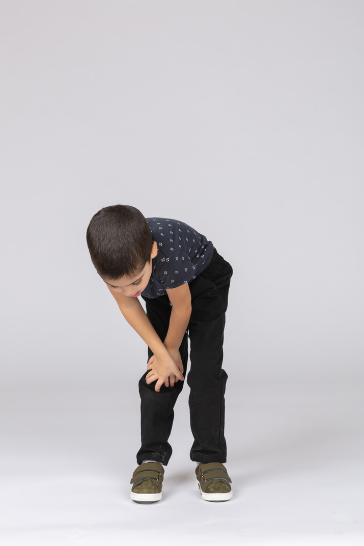 Front view of a boy bending down and touching knee