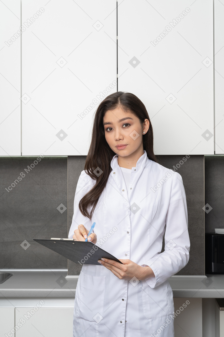 Front view of a young female taking notes and looking at camera