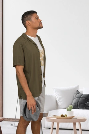 A man standing in a living room holding a hat