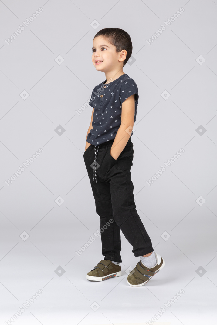 Вид сбоку милый мальчик позирует с руками в карманах