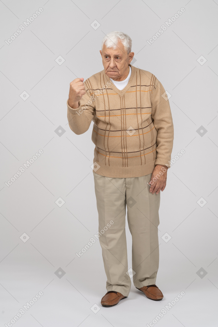 Vue de face d'un vieil homme en colère dans des vêtements décontractés montrant le poing
