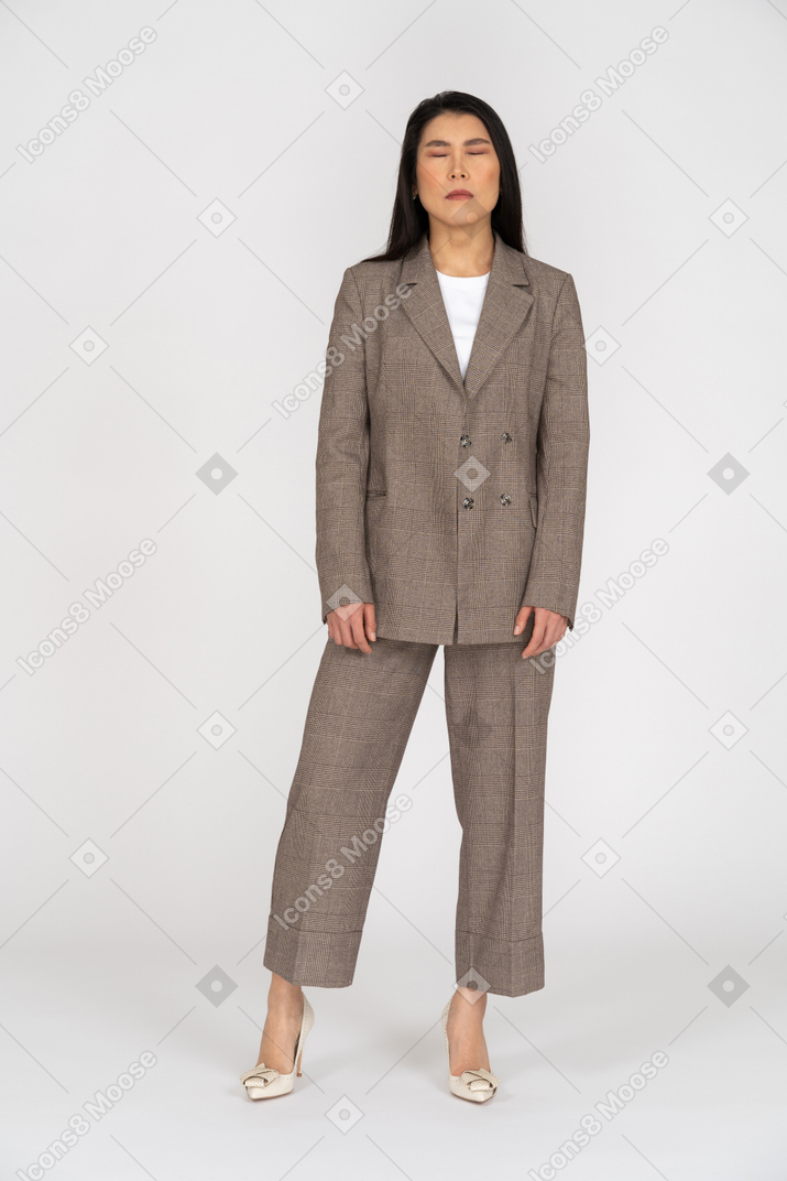 Front view of a young lady in brown business suit closing her eyes
