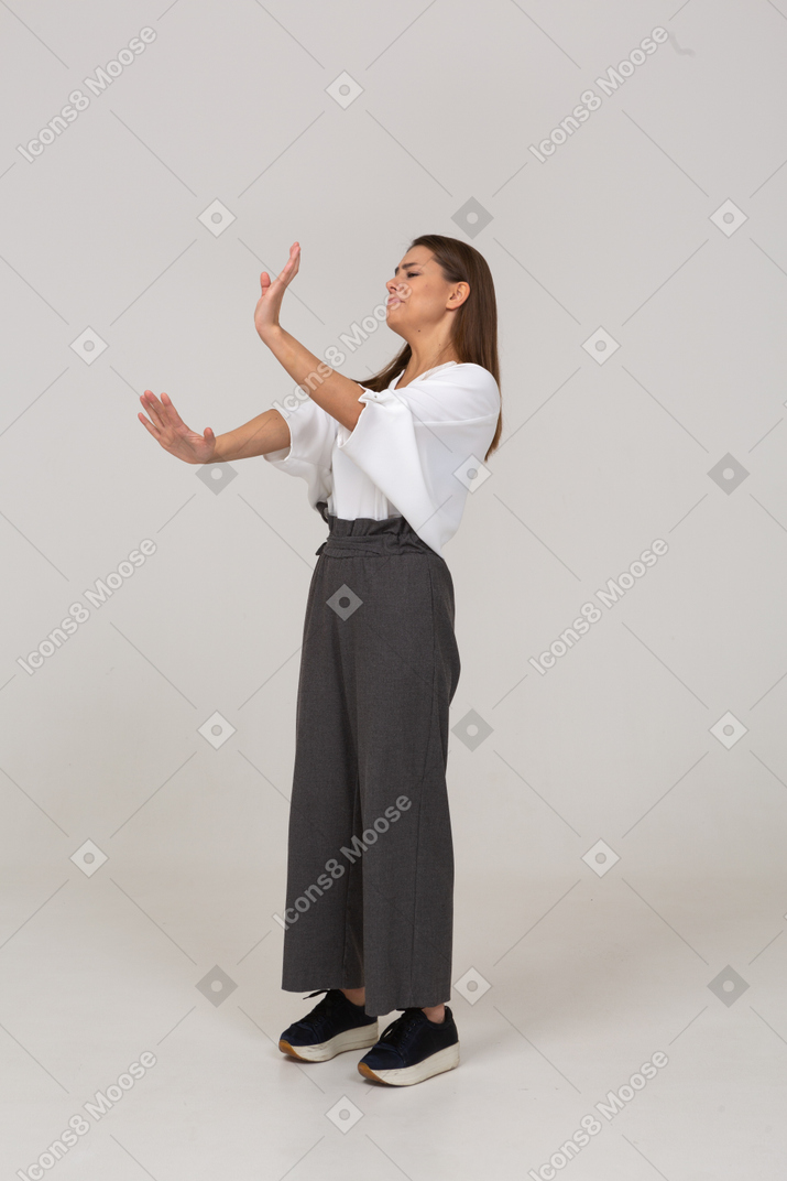 一位不情愿的年轻女士在办公室服装伸出手臂的侧视图