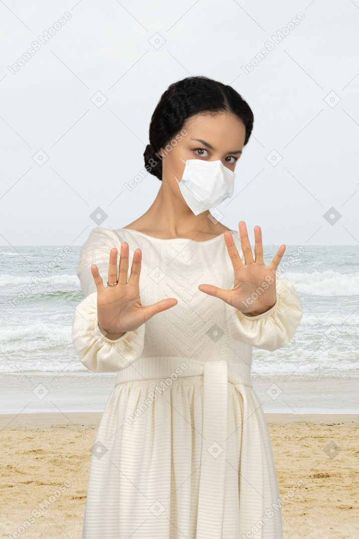 Bella donna mascherata in piedi su una spiaggia