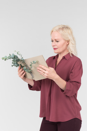 A nice-looking middle-aged blonde woman in a burgundy shirt and a craft notebook in her hand