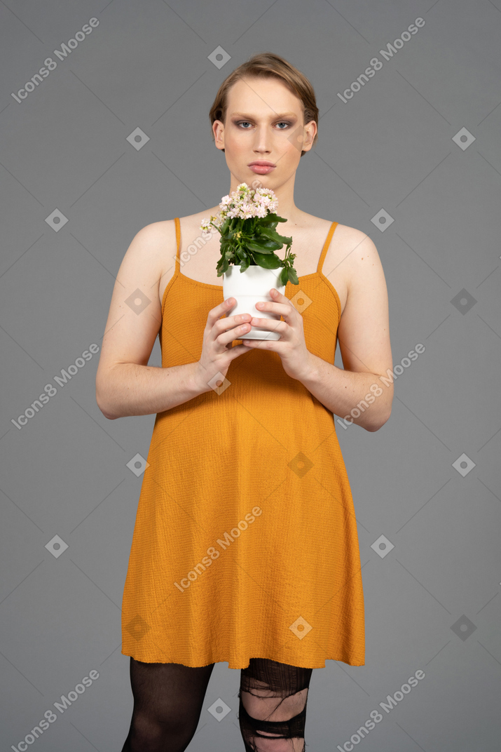 Portrait of a young transgender person holding pot of flowers
