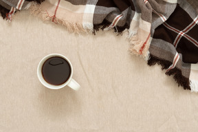 Uma xícara de café preto e uma manta