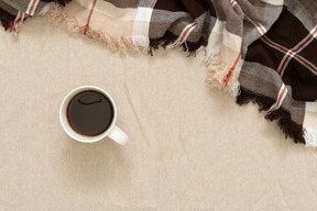 Eine tasse schwarzen kaffee und ein plaid