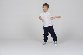 Front view of cheerful child standing with his arms bent