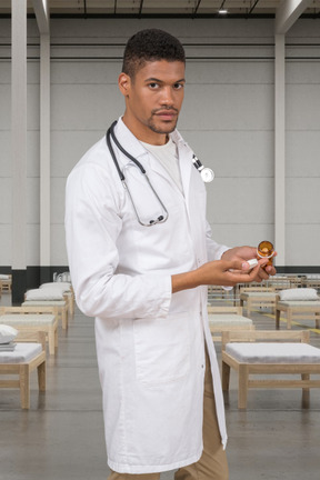 A man in a white lab coat holding pills