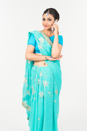 Junge indische tänzerin im blauen sari hört aufmerksam auf telefongespräch