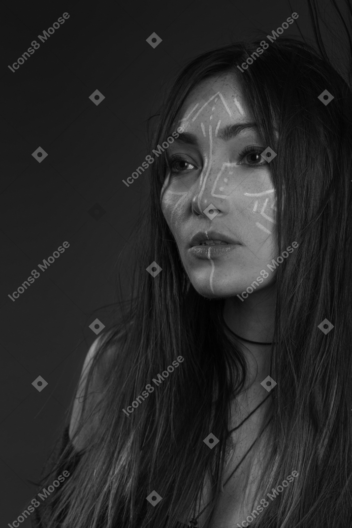Noir three-quarter portrait of a young female with ethnic facial art