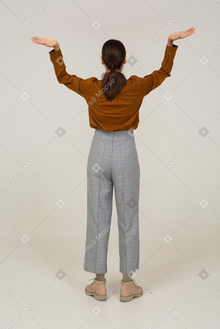 一位身着马裤和衬衫的年轻亚洲女性举手的背影