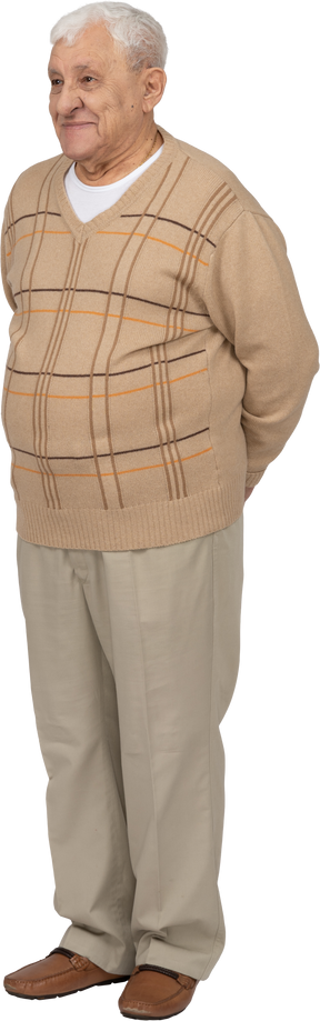 Vue de face d'un vieil homme heureux dans des vêtements décontractés debout avec les mains derrière le dos