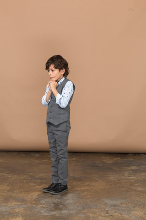 Vista lateral de um menino pensativo de terno cinza