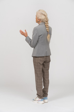 Rear view of an old lady in suit gesturing