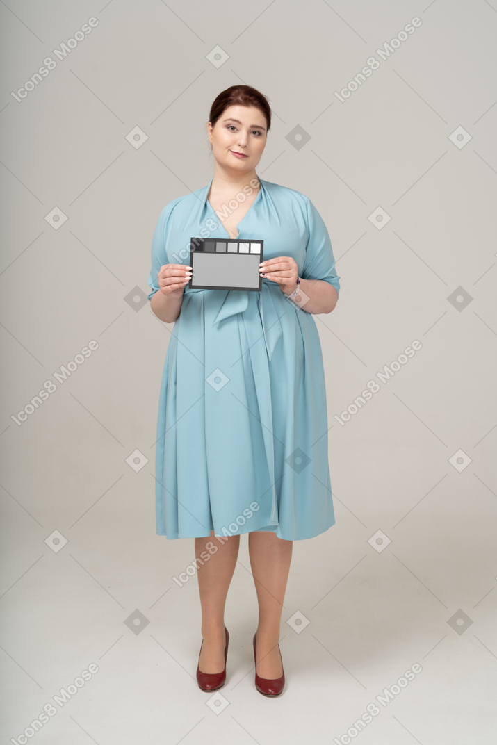 Front view of a woman in blue dress showing a card