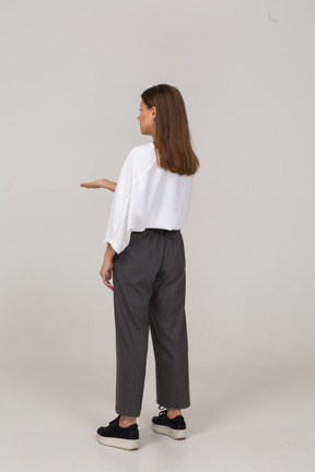 Three-quarter back view of a young lady in office clothing asking for something