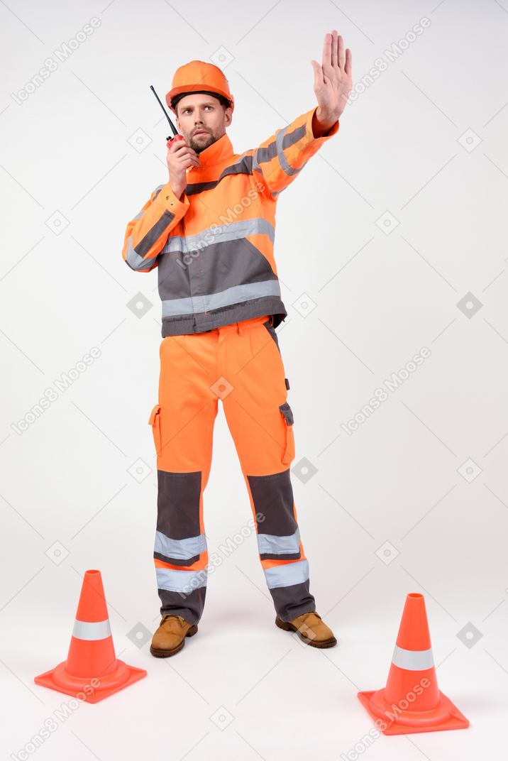 Construction worker using radio phone and showing stop gesture