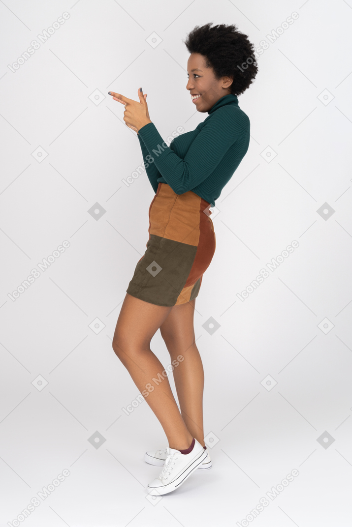 Ritratto della ragazza africana sorridente che fa un gesto della rivoltella nel profilo