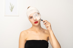 Young woman looking through magnifying glass