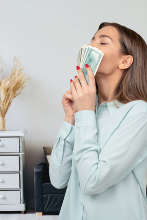 A young woman smelling a stack of money