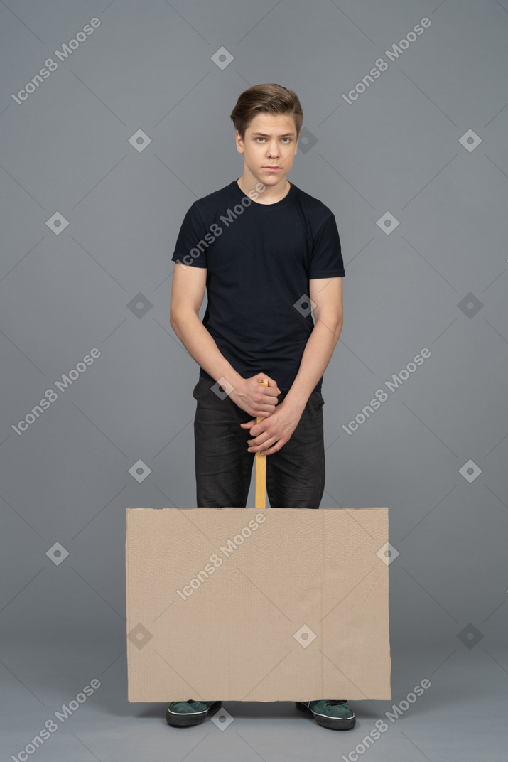 Serious young man holding a poster upside down