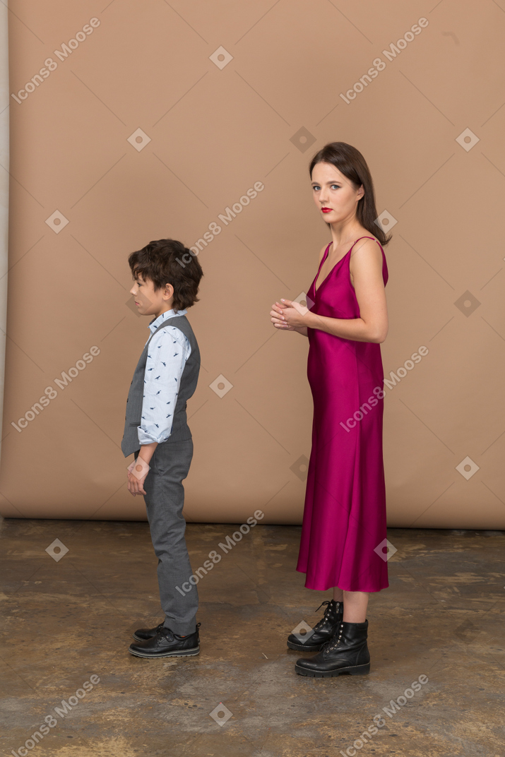 Mujer joven en vestido rojo y niño parado quieto
